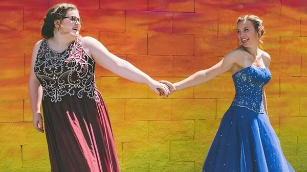 Dos mujeres en vestidos elegantes se toman de la mano en un evento de la Chilliwack Secondary School.