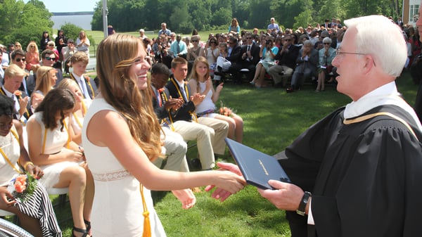Un grupo de graduados celebra la ceremonia de graduación al aire libre en el campus de la Christchurch School.