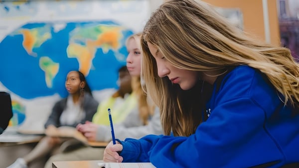 Una estudiante de la Christian Life School se concentra en una tarea frente a un colorido mapa del mundo en la pared.