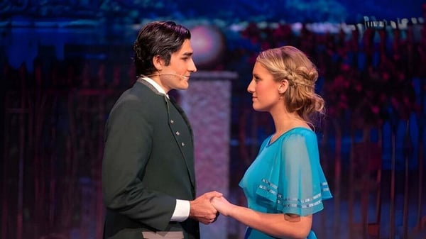 Dos personas se toman de las manos en el escenario frente a un fondo colorido en el campus de las Christian Unified Schools.