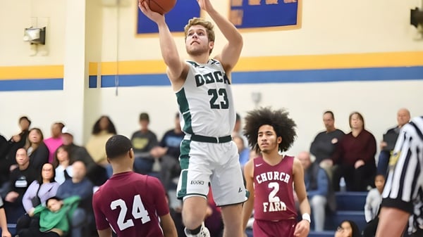 Un jugador de baloncesto de la Church Farm School salta para lanzar a la canasta frente a espectadores en el fondo.