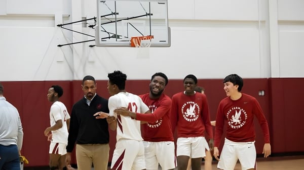 Un grupo de estudiantes de la Church Farm School está en la cancha de baloncesto junto a una canasta.
