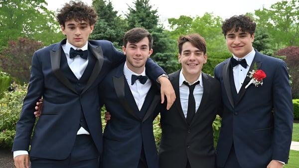 Un grupo de jóvenes en ropa formal está de pie en el campus del Cistercian College en un área verde.