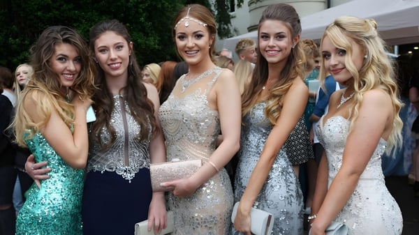 Un grupo de jóvenes mujeres vestidas formalmente posa frente a edificios y áreas verdes en el campus de la City of London Freemen’s School.