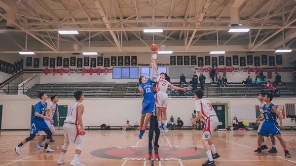 Estudiantes de la City Vancouver Academy High School juegan un partido de baloncesto frente a espectadores en las gradas.