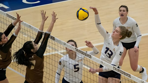Estudiantes de la City Vancouver Academy High School juegan un partido de voleibol con la pelota sobre la red.