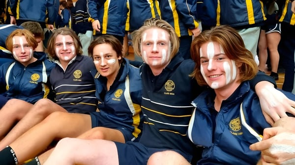 Un grupo de estudiantes de Clare High School posan con uniformes idénticos en una ceremonia de graduación.