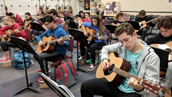 Un grupo de estudiantes en el Clark County School District toca guitarras y escucha atentamente en la clase de música.