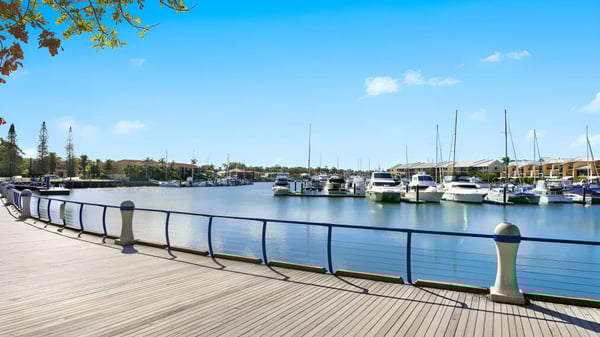 Un muelle de madera pasa junto a una tranquila marina con veleros y yates en el terreno de la Cleveland District State High School.