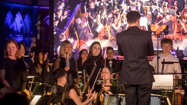 La orquesta del Clifton College realiza un concierto en el escenario bajo la dirección del director.