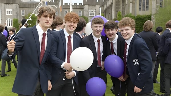 Un grupo de estudiantes sostiene globos en el campus del Clongowes Wood College durante un evento.
