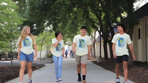 Un grupo de estudiantes de la Clovis High School camina juntos por un camino bordeado de árboles.