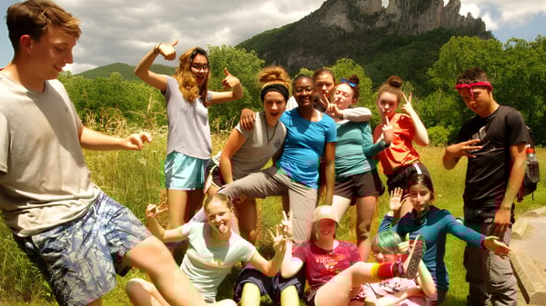 Un grupo de estudiantes de la Cnoc Mhuire Secondary School reunidos al aire libre frente a un paisaje montañoso con vegetación exuberante.