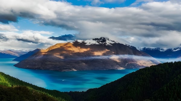 Una montaña se eleva sobre un lago turquesa con bosques verdes en el terreno del Coffs Harbour Senior College.