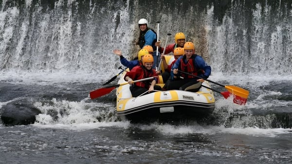 Estudiantes de la Colaiste Chiarain Athlone navegan en una balsa por un lado de una cascada.