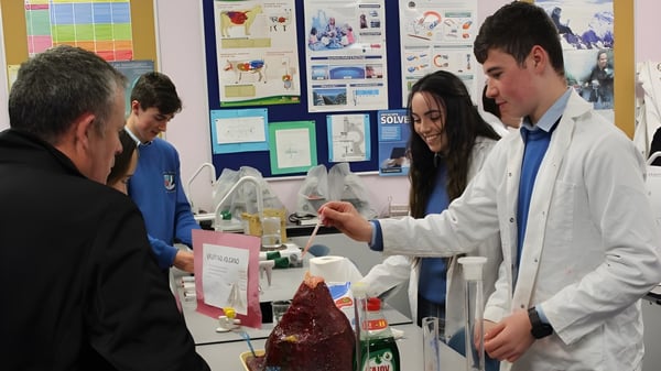 Estudiantes de la Colaiste Chiarain Athlone se reúnen en el laboratorio alrededor de una mesa con materiales de enseñanza.