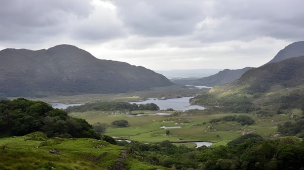 Un valle verde con un río serpenteante bajo un cielo nublado cerca de la Coláiste Choilm.