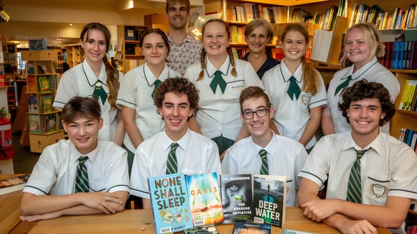 Un grupo de estudiantes de Coláiste Chríost Rí posan juntos en una librería y sostienen varios libros.