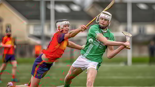 Dos deportistas en uniformes realizan un enfrentamiento físico en el campo de Coláiste Íosagáin.