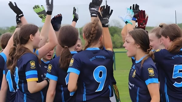 Un grupo de jóvenes futbolistas en camisetas azules y blancas celebra juntos en el campo de deportes de Coláiste Mhuire (Ballygar).