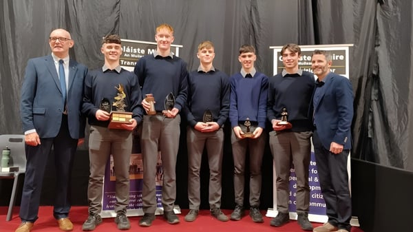 Un grupo de personas en ropa formal está de pie en el escenario de la Coláiste Mhuire Mullingar.