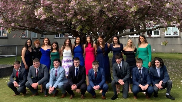 Un grupo de estudiantes de Colaiste Mhuire (Tourmakeady) está frente a un cerezo en flor.
