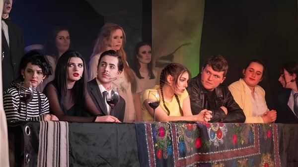 Un grupo de estudiantes se encuentra en un escenario frente a un fondo colorido en el campus de la Colaiste Muire (Cobh).