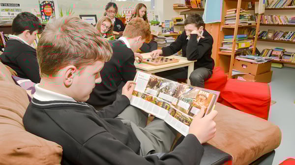 Estudiantes de Coláiste Pobail Acla examinan juntos fotos y documentos en una mesa.