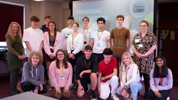 Un grupo de estudiantes del College of Richard Collyer posan juntos en una sala con un letrero de 'Personal' al fondo.