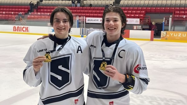 Dos estudiantes del College Saint-Bernard están con medallas sobre el hielo de una arena de hockey.