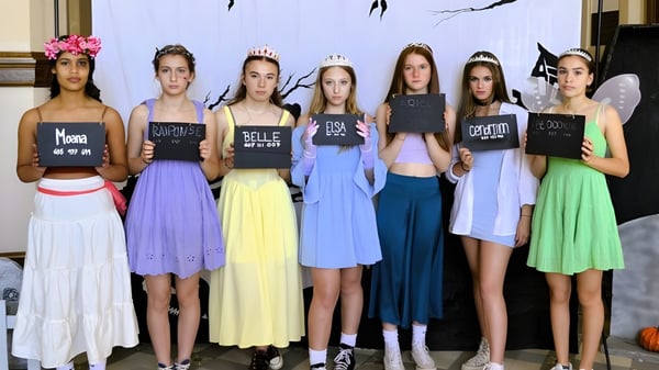Un grupo de jóvenes mujeres sostiene carteles con textos frente a un patrón abstracto en el campus del Collège de Sainte-Anne-de-la-Pocatière.