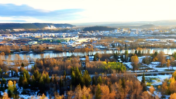 Toma aérea muestra la ciudad con montañas cubiertas de nieve y un lago con vegetación otoñal cerca de la College Heights Secondary School.