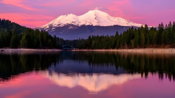 Un lago tranquilo con una pequeña tienda en primer plano refleja las montañas nevadas y el cielo colorido en el terreno del Collège Churchill High School.