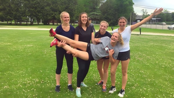 Un grupo de jóvenes estudiantes está riendo en un área de césped en el parque del campus del Collingwood Collegiate Institute.