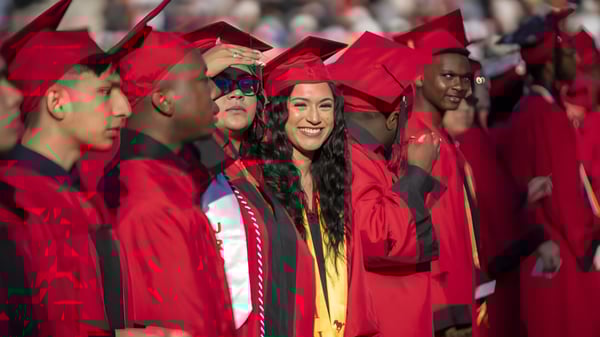 Un grupo de egresadas y egresados del Columba College celebra juntos en togas de graduación rojas.