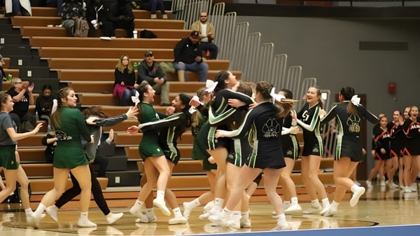 Un grupo de animadoras de la Comstock Park High School realiza una actuación en la cancha de baloncesto frente a espectadores.