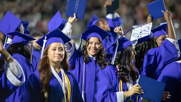 Un grupo de graduadas y graduados de la Cornafulla National School celebra con togas de graduación violetas y diplomas.