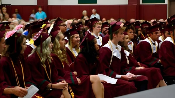 Graduadas y graduados de la Covenant Christian High School llevan sus togas de graduación en un auditorio.