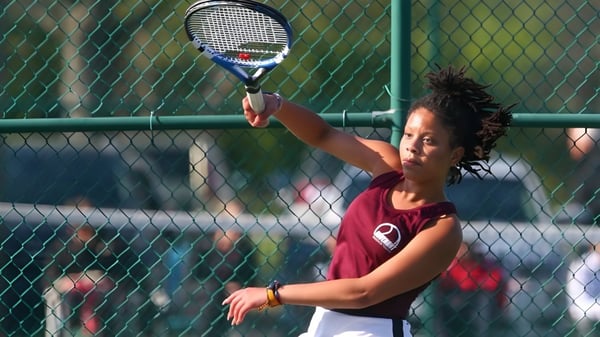 Una estudiante de la Covenant Christian High School está con una raqueta de tenis en el campo de tenis.
