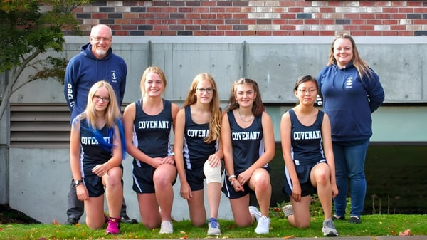 Un grupo de estudiantes de la Covenant High School está junto a una pared de ladrillo.