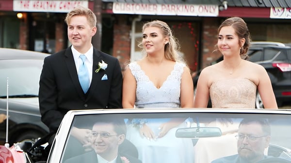 Tres personas están frente a un edificio en el terreno de la Cowichan Secondary School en un entorno urbano.