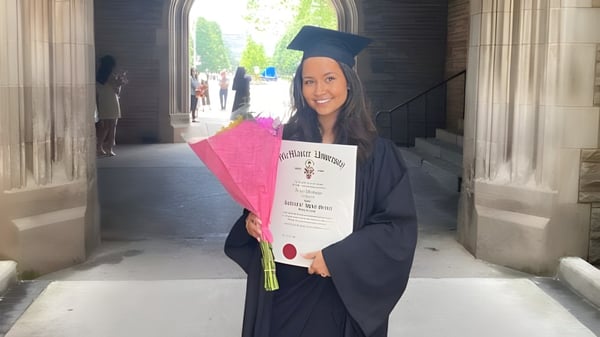 Una estudiante de la Craig Kielburger Secondary School sostiene un certificado en la entrada con la toga de graduación.