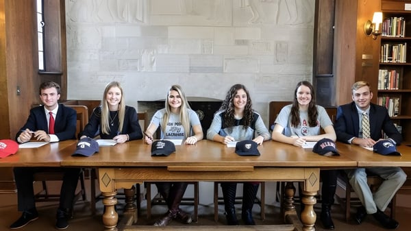 Seis estudiantes trabajan juntos en una mesa de madera en la biblioteca de Cranbrook Schools.