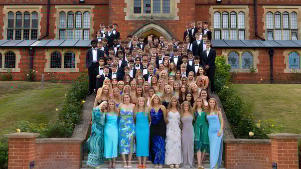 Un grupo de personas en ropa formal está de pie frente al edificio histórico de la Cranleigh School.