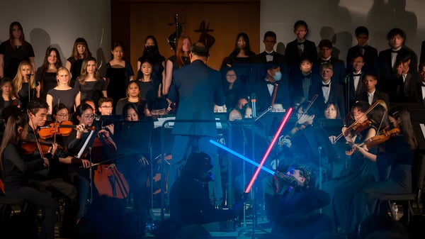 Un grupo de estudiantes de la Crean Lutheran High School se presenta en un escenario con iluminación azul.