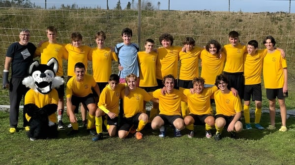 Un grupo de jóvenes futbolistas en camisetas amarillas posan en un campo en el campus del Crescent Collegiate.
