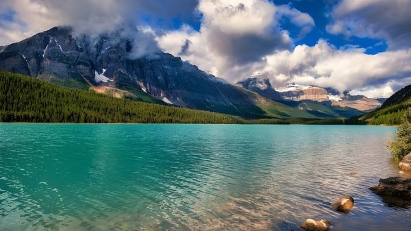 Un tranquilo lago de montaña con picos nevados y bosques, rodeado de montañas, fuera del campus del Crescent Collegiate.