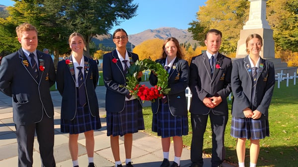 Un grupo de estudiantes en uniformes escolares está frente a un paisaje montañoso otoñal en el terreno del Cromwell College.