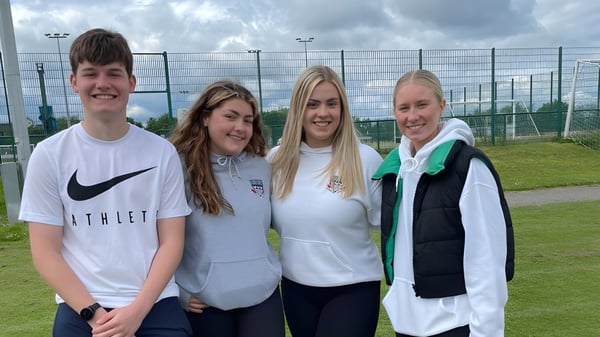 Cuatro estudiantes están en un campo deportivo de la Currie Community High School.