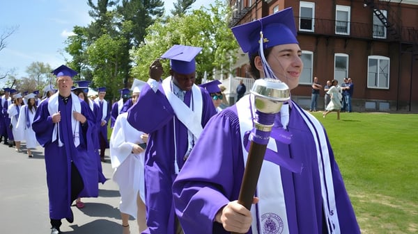 Graduados en togas moradas y birretes caminan por el campus de la Cushing Academy.